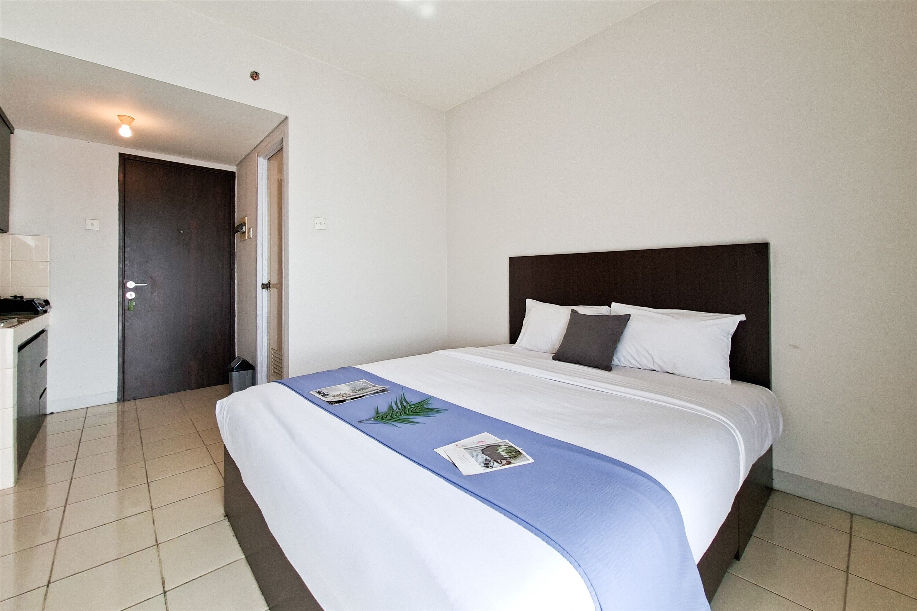 A hotel room with a bed, a desk, and a door.