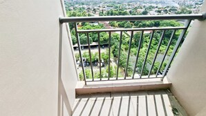 Un balcón con barandilla de metal que da a un barrio residencial con casas y vegetación.