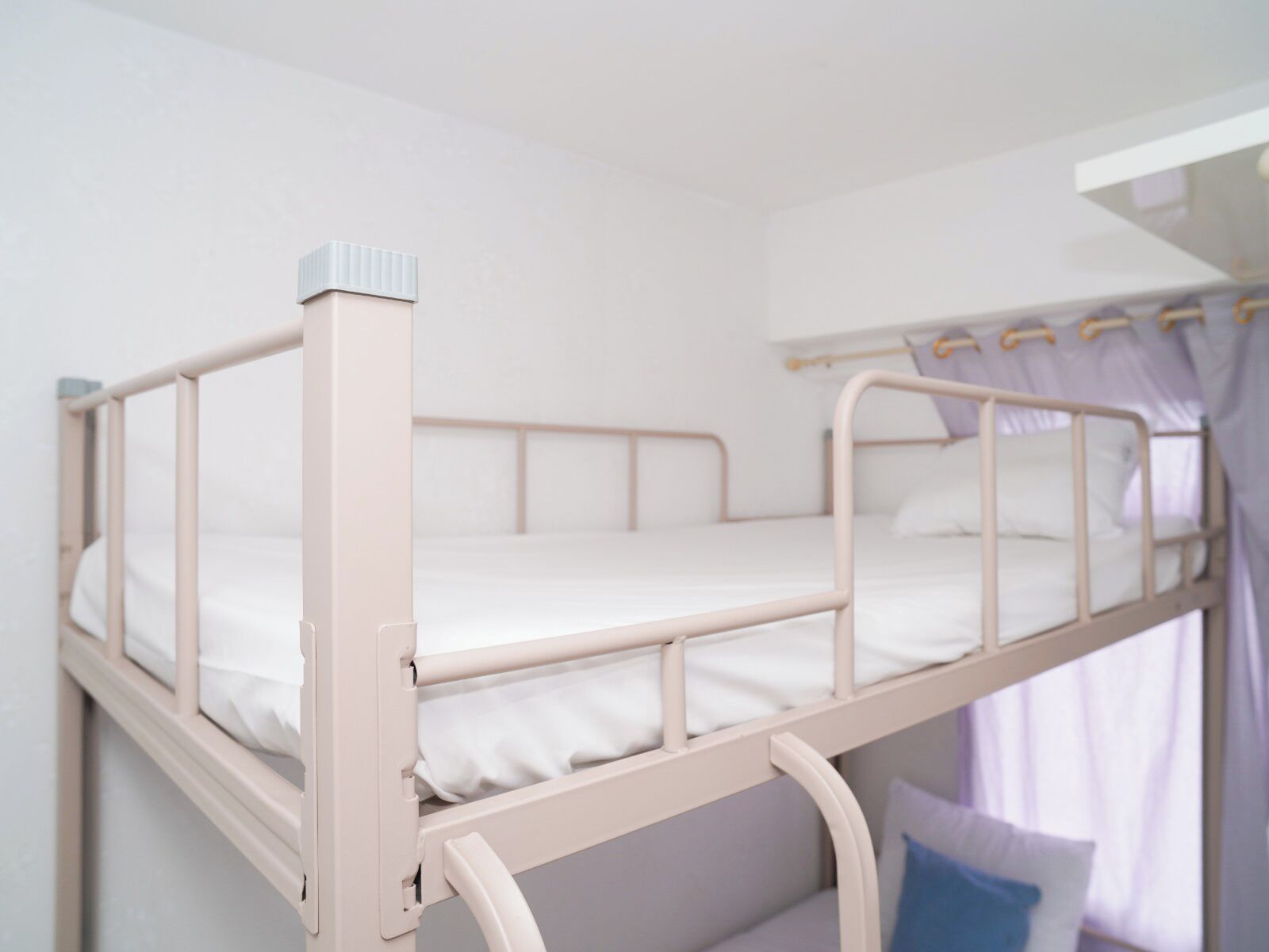 Una cama litera con escritorio extraíble, ropa de cama blanca y una cortina.