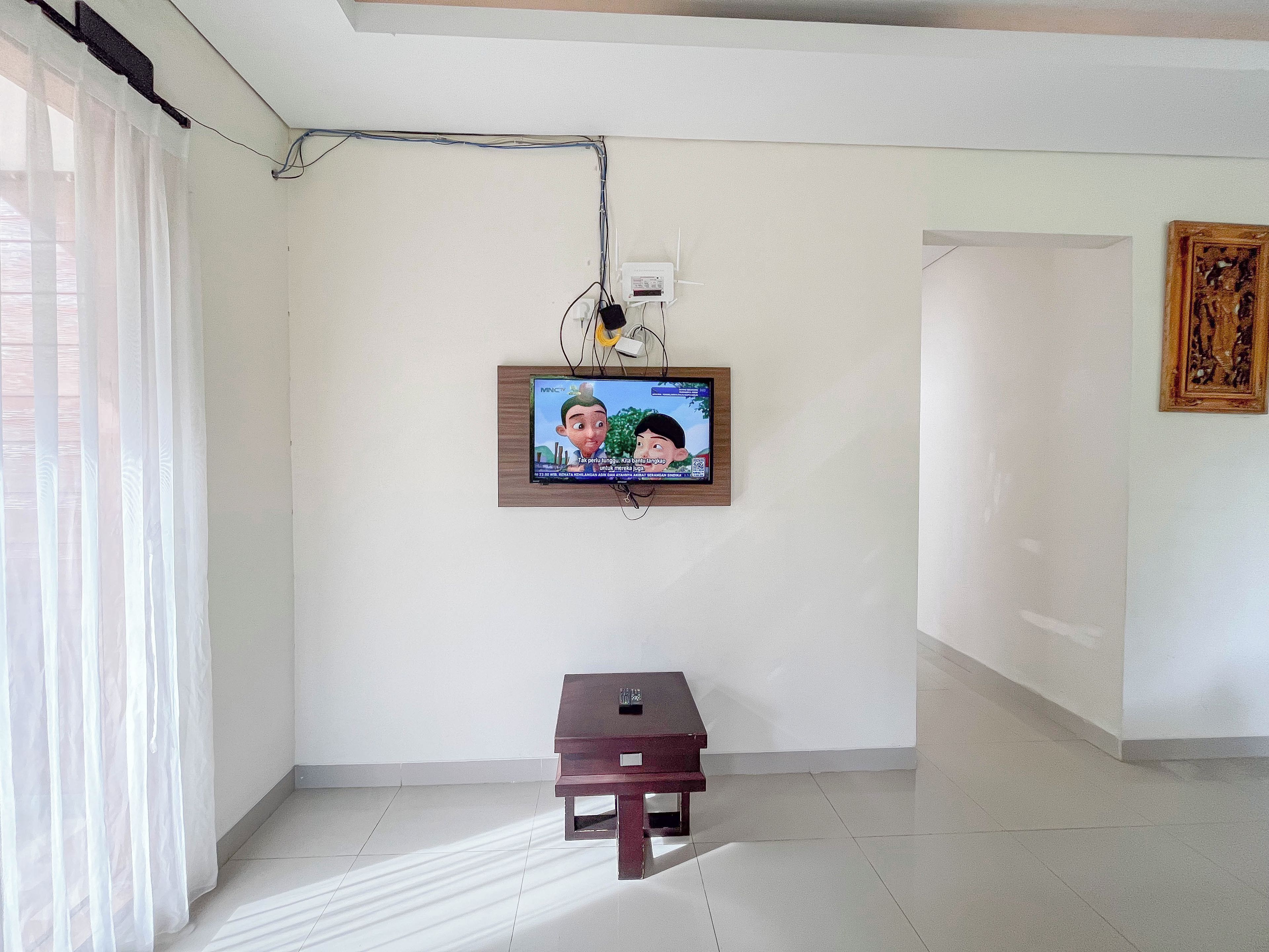 Une pièce avec un téléviseur fixé au mur, une petite table et un tableau accroché au mur.