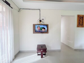 Een kamer met een aan de muur bevestigde televisie, een kleine tafel en een schilderij.