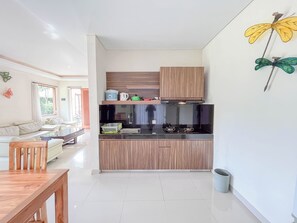 Une cuisine moderne avec des meubles en bois, un plan de travail noir et un coin repas comprenant une table et des chaises en bois.