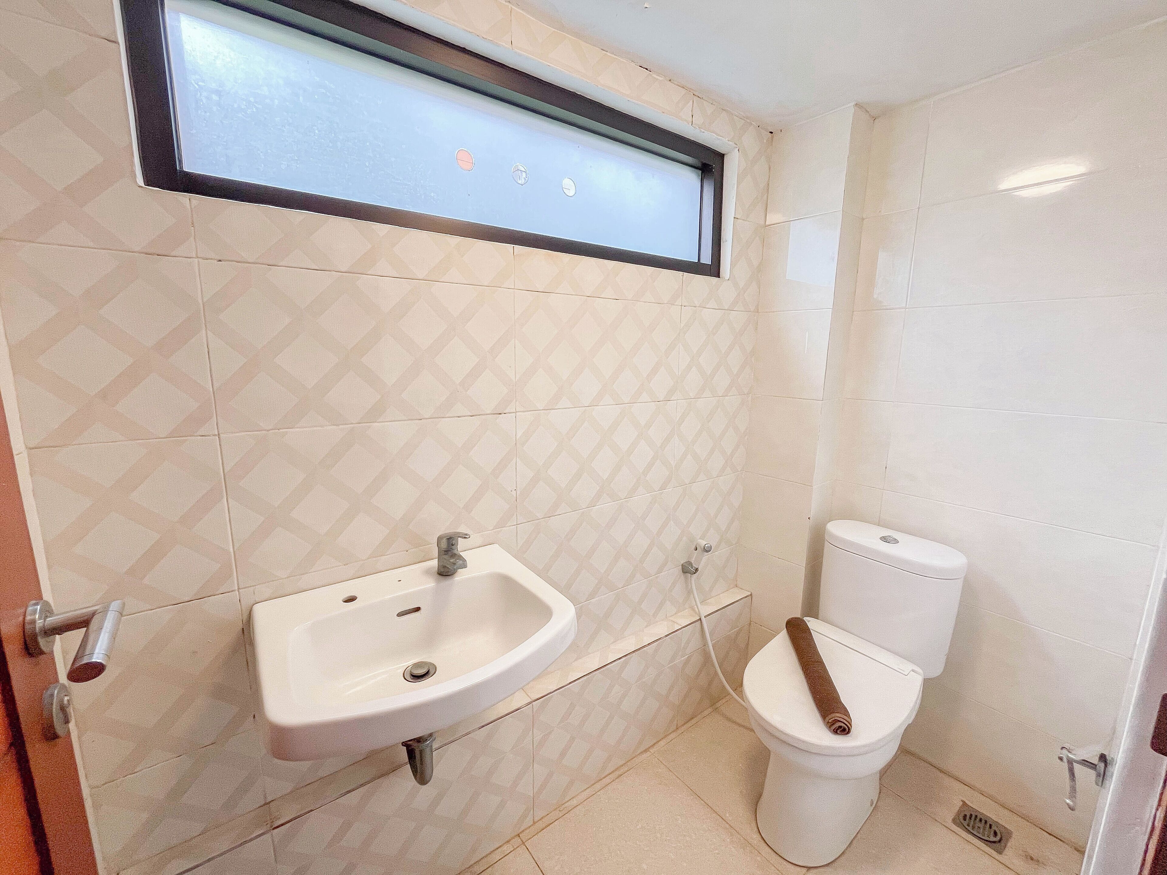 A bathroom with a sink, toilet, and a window above the sink.