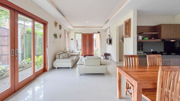 Un amplio espacio de sala con un sofá grande, una mesa de comedor con sillas y una cocina con armarios y estufa.