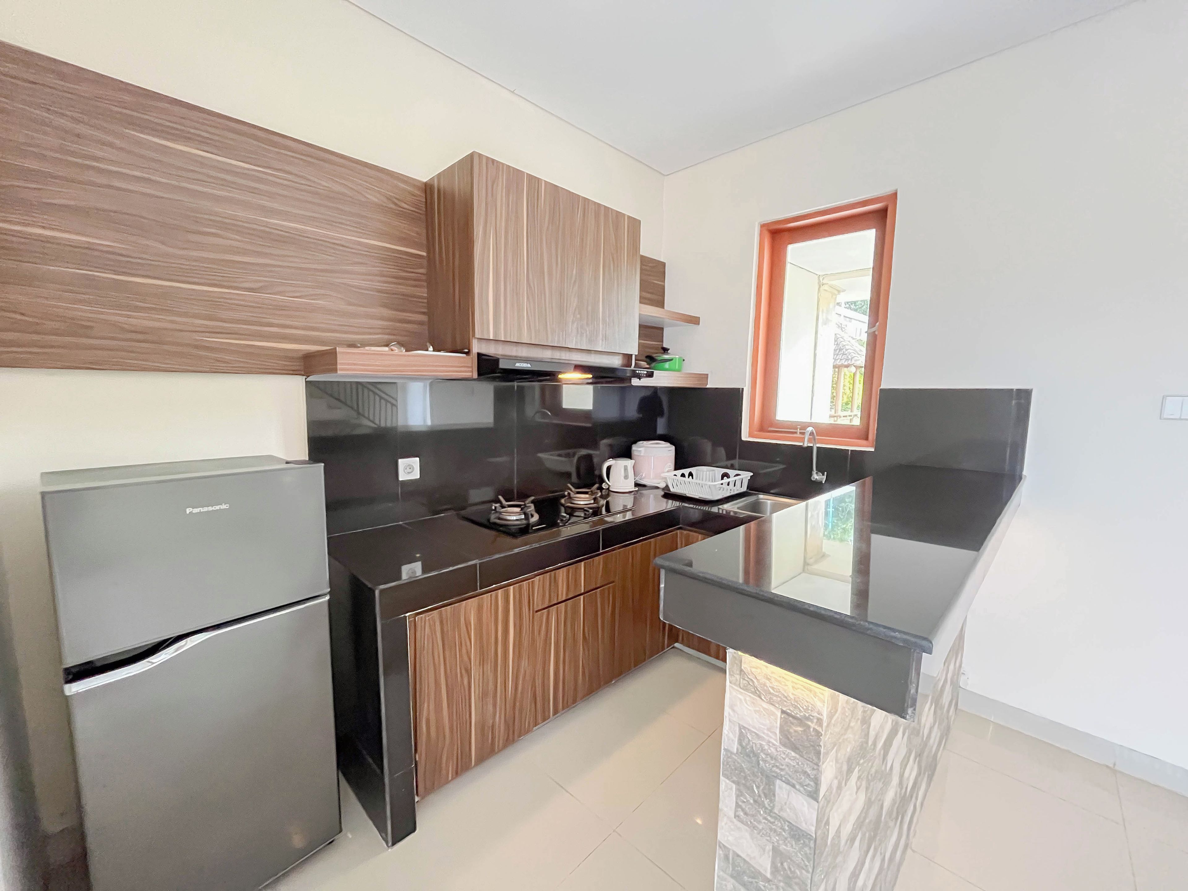A modern kitchen with a refrigerator, stove, and wooden cabinets.