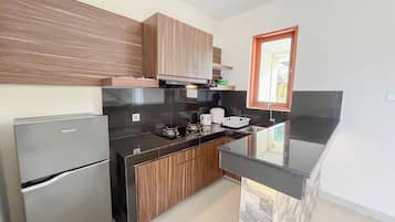 A modern kitchen with a refrigerator, stove, and wooden cabinets.