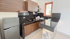 A modern kitchen with a refrigerator, stove, and wooden cabinets. - Spacious And Homey 3Br At Villa Casa De Uli (Jimbaran)