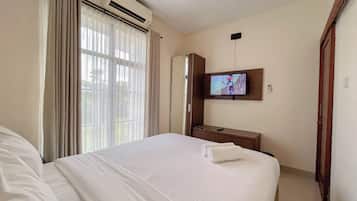 Ein Hotelzimmer mit Bett, Wandfernseher, Klimaanlage und einem Vorhangfenster.