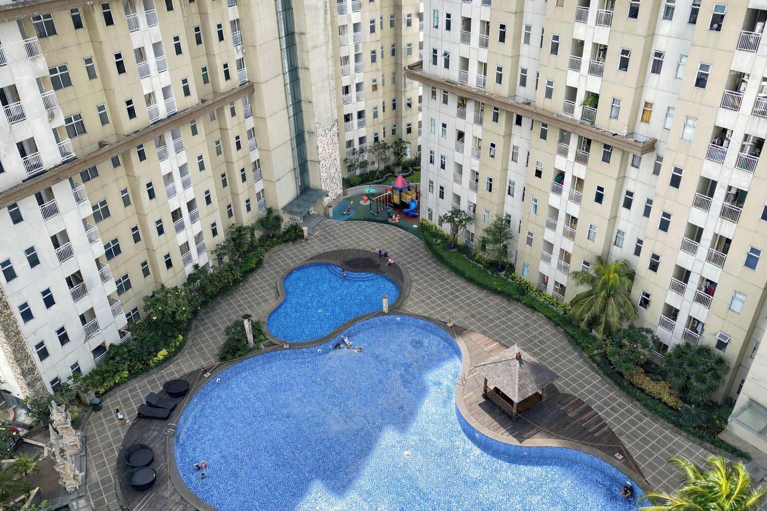 Un edificio residencial con varios balcones, un patio central con piscina y una zona de juegos infantiles.