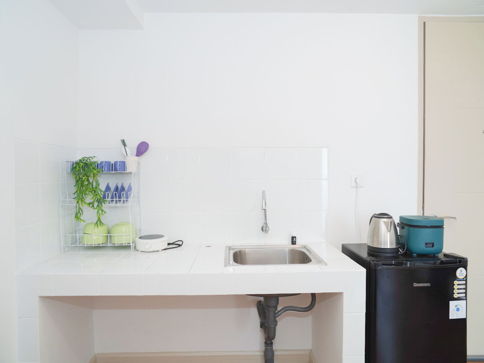 Una cocina con encimera blanca, pileta de acero inoxidable y cafetera negra.