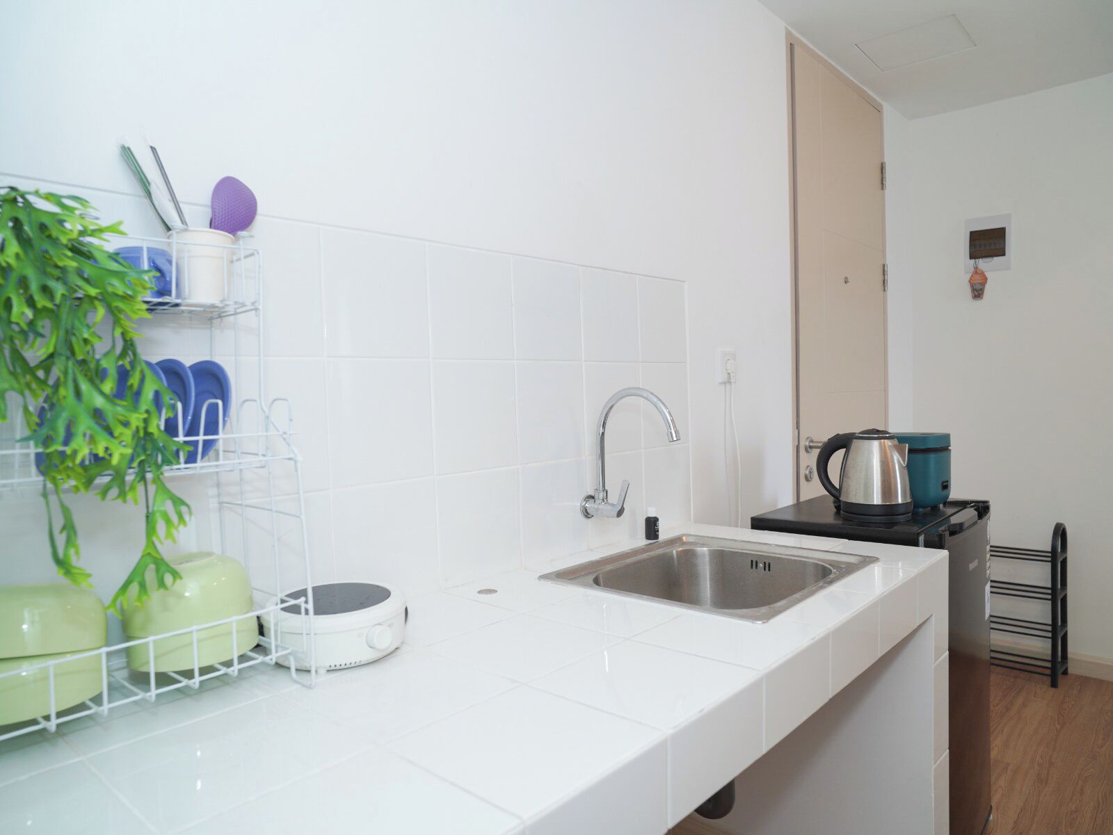 A modern kitchen with white countertops, a stainless steel sink, and a coffee maker.