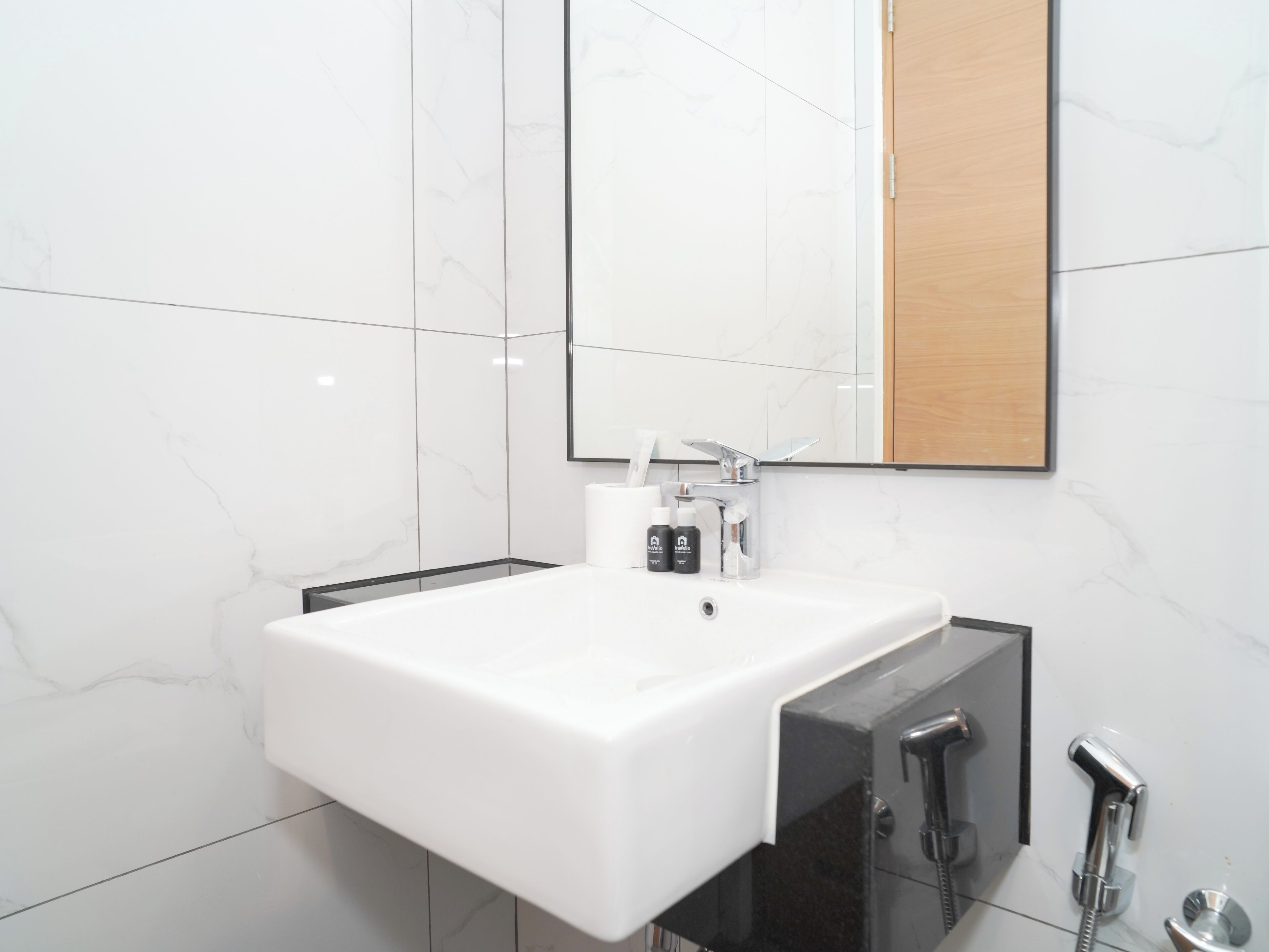 A modern bathroom with a white sink, a mirror, and a black cabinet.