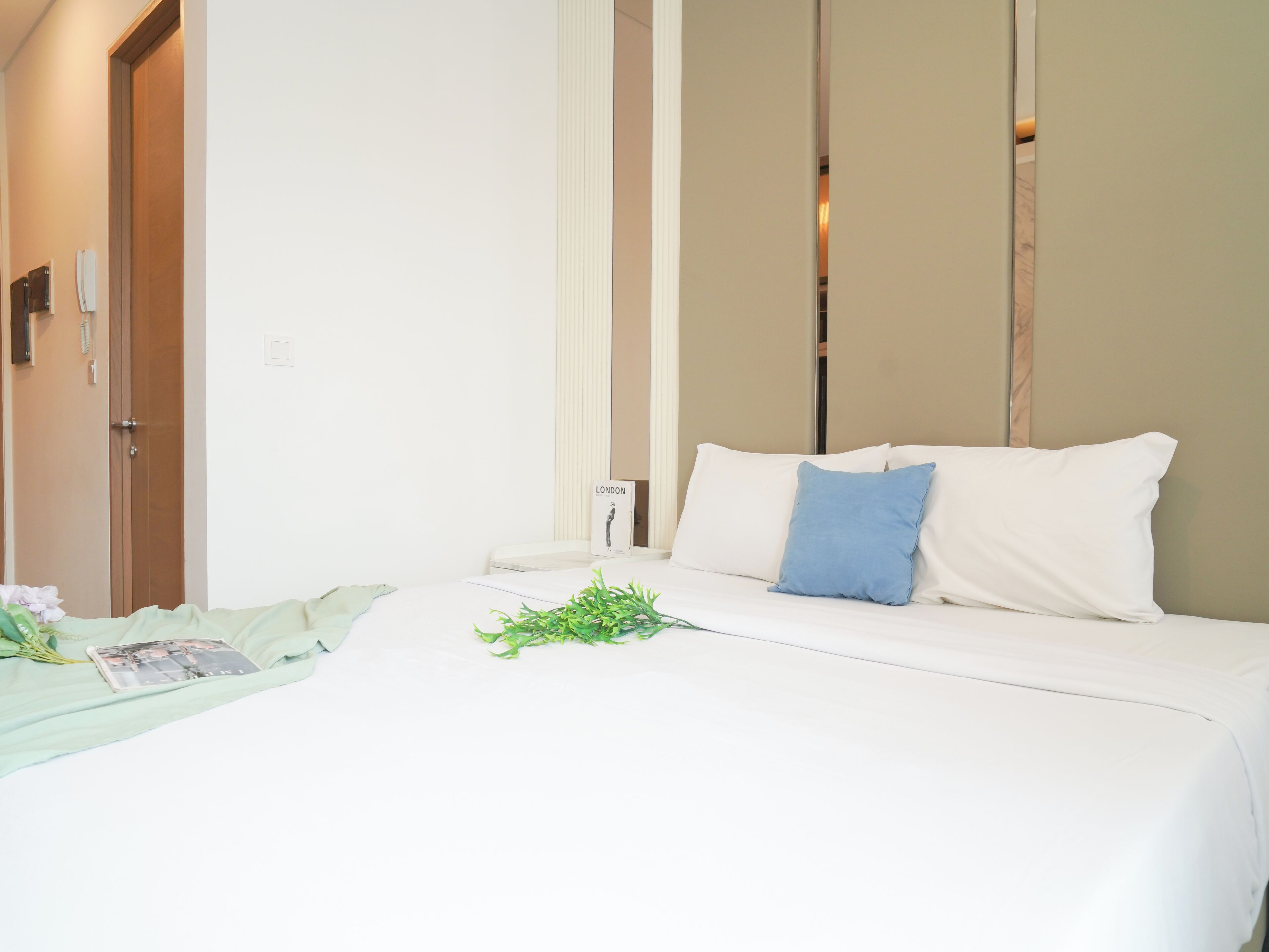 A hotel room with a bed, a nightstand, a mirror, and a door.