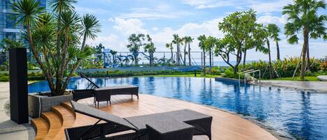 A poolside area with lounge chairs and a view of the ocean.