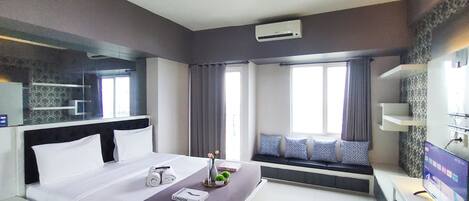 A modern hotel room with a large bed, a bedside table, a TV, and a window with curtains.