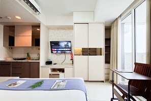 Una habitación de hotel moderna con una cama, un escritorio, un televisor y una ventana con cortinas.