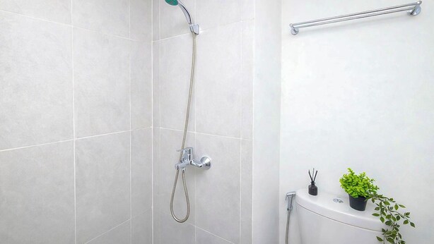 A modern bathroom with a shower, a towel rack, and a small potted plant. - Contemporary And Cozy Studio Apartment Lrt City Sentul - Royal Sentul Park (Bogor)
