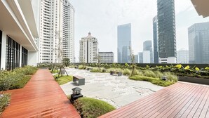 Un jardín en la azotea con un sendero de madera, bancos y una pequeña fuente.