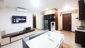 Una cocina compacta con comedor, un televisor de pantalla plana en la pared y un refrigerador.