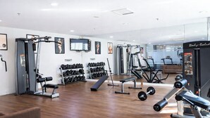 Ein modernes Fitnessstudio mit verschiedenen Trainingsgeräten, Gewitterregalen und einem Laufband.