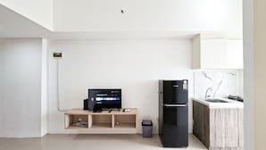 Una cocina moderna con un refrigerador empotrado, una estantería de madera y un pequeño cubo de basura.