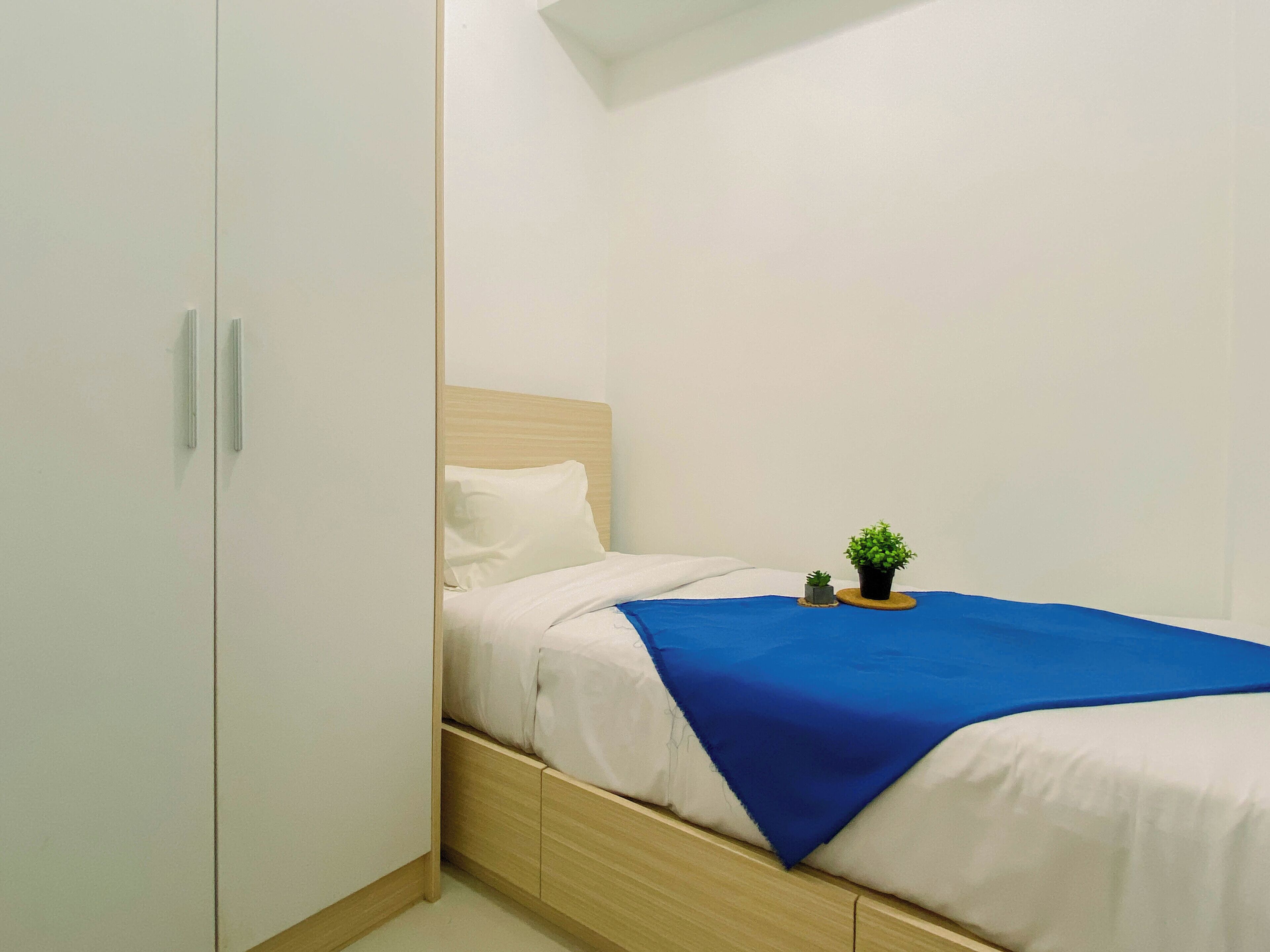 Una camera da letto con un letto, una piccola pianta in vaso e una coperta blu.