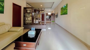Een moderne hotellobby met een bank, een salontafel en een keuken in de achtergrond.