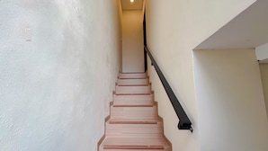 A staircase with wooden steps and a black handrail, leading to a landing with a light fixture. - Serene Designed And Homey Studio At Villa Casa De Uli (Nusa Dua)