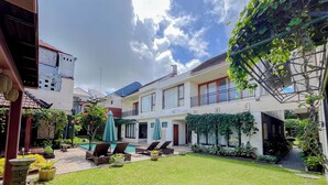 A courtyard with a swimming pool, lounge chairs, and a well-maintained lawn. - Serene Designed And Homey Studio At Villa Casa De Uli (Nusa Dua)