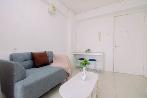 Una sala de estar moderna con un sofá gris, una mesa de centro blanca con un florero y una puerta blanca.