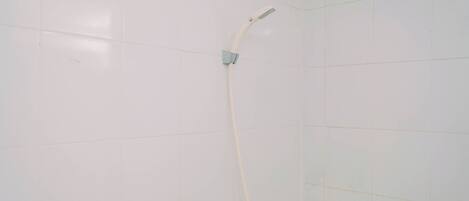 A shower with a handheld showerhead mounted on a wall.