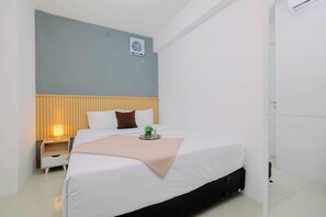 Una habitación de hotel moderna con una cama, una mesita de noche y una planta pequeña.