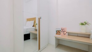 A minimalist bedroom with a bed, a bedside table, and a mirror. - Compact With Minimalist Designed 2Br At Bassura City Apartment (Jakarta)