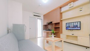 A modern living room with a sofa, a wooden coffee table, and a television. - Serene And Warm 2Br At Apartment Bassura City (Jakarta)
