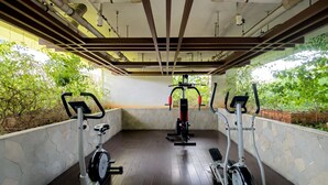 An indoor gym with exercise equipment, stone walls, and a wooden floor. - Serene And Warm 2Br At Apartment Bassura City (Jakarta)