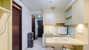 Una cocina compacta con refrigerador, pileta y una mesa de comedor con sillas.