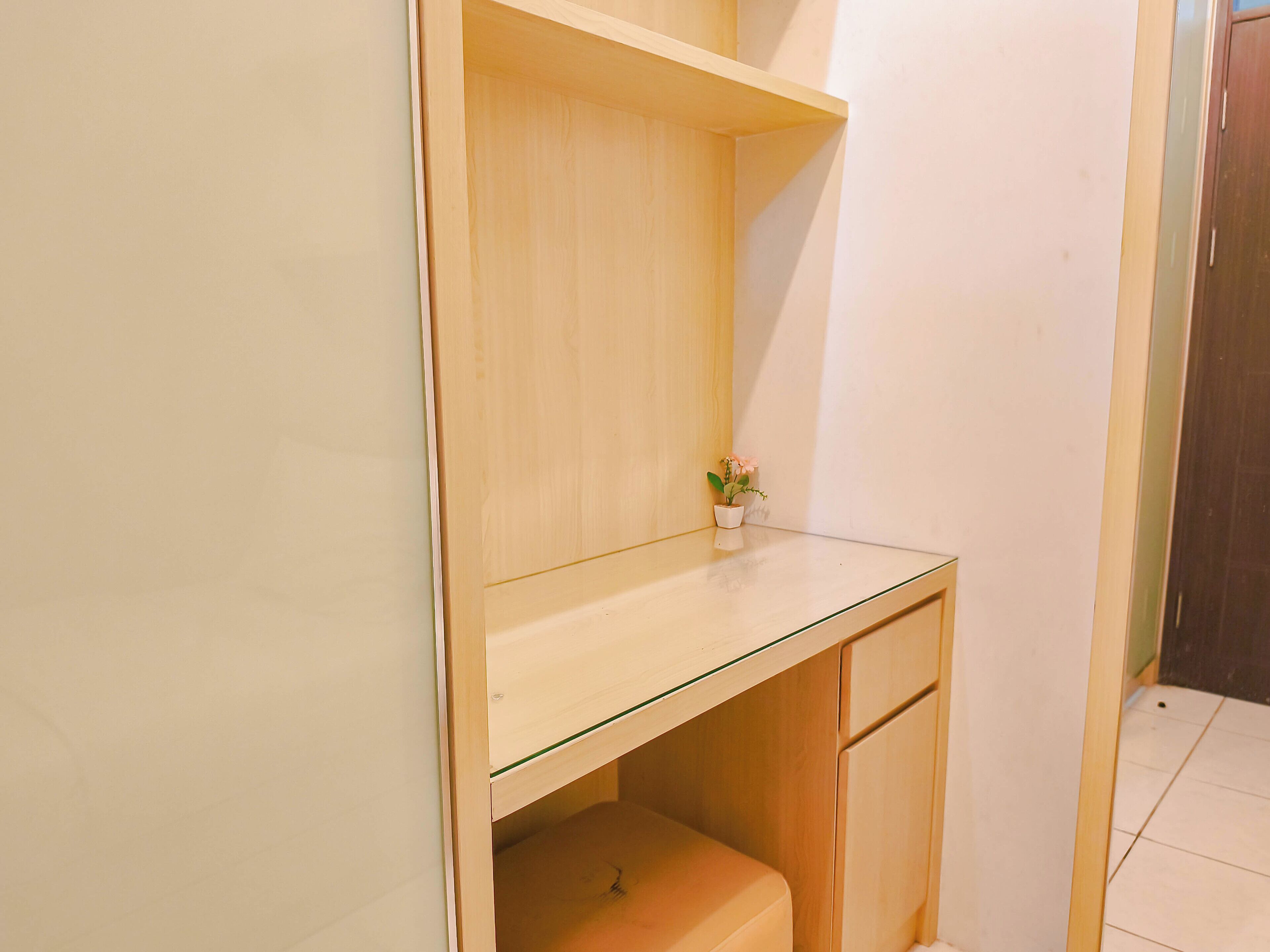 A small wooden desk with a glass top and a small potted plant.