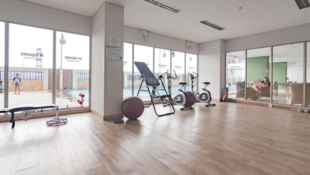 Un gimnasio con equipamiento de ejercicio, ventanas amplias y vistas a una piscina.