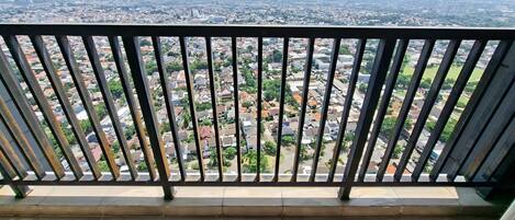 Een balkon met een metalen hekwerk dat uitkijkt over een stadsgezicht.