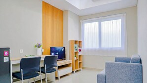 A modern room with a desk, chairs, a TV, a bookshelf, and a window. - Charming 1Br Apartment Lrt City Sentul - Royal Sentul Park (Bogor)