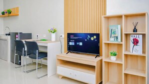 A modern office space with a desk, chairs, a television, and a bookshelf. - Charming 1Br Apartment Lrt City Sentul - Royal Sentul Park (Bogor)