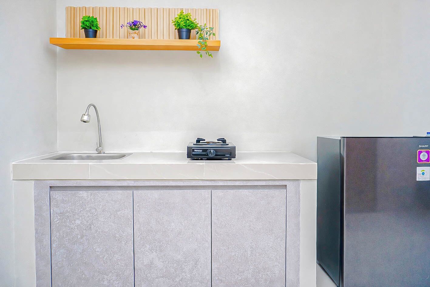 Una cocina con refrigerador de acero inoxidable, lavamanos empotrado y microondas sobre la encimera.
