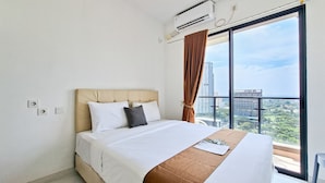 Habitación de hotel con cama, ventana con cortinas, unidad de aire acondicionado y vista a edificios.