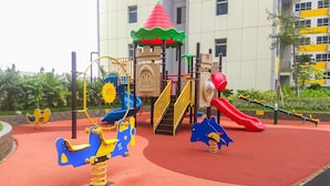 Ein Spielplatz mit Rutsche, Schaukeln und einer Kletterkonstruktion.