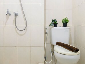 Ein Badezimmer mit Toilette, Dusche und zwei Blumentöpfen auf dem Tank.