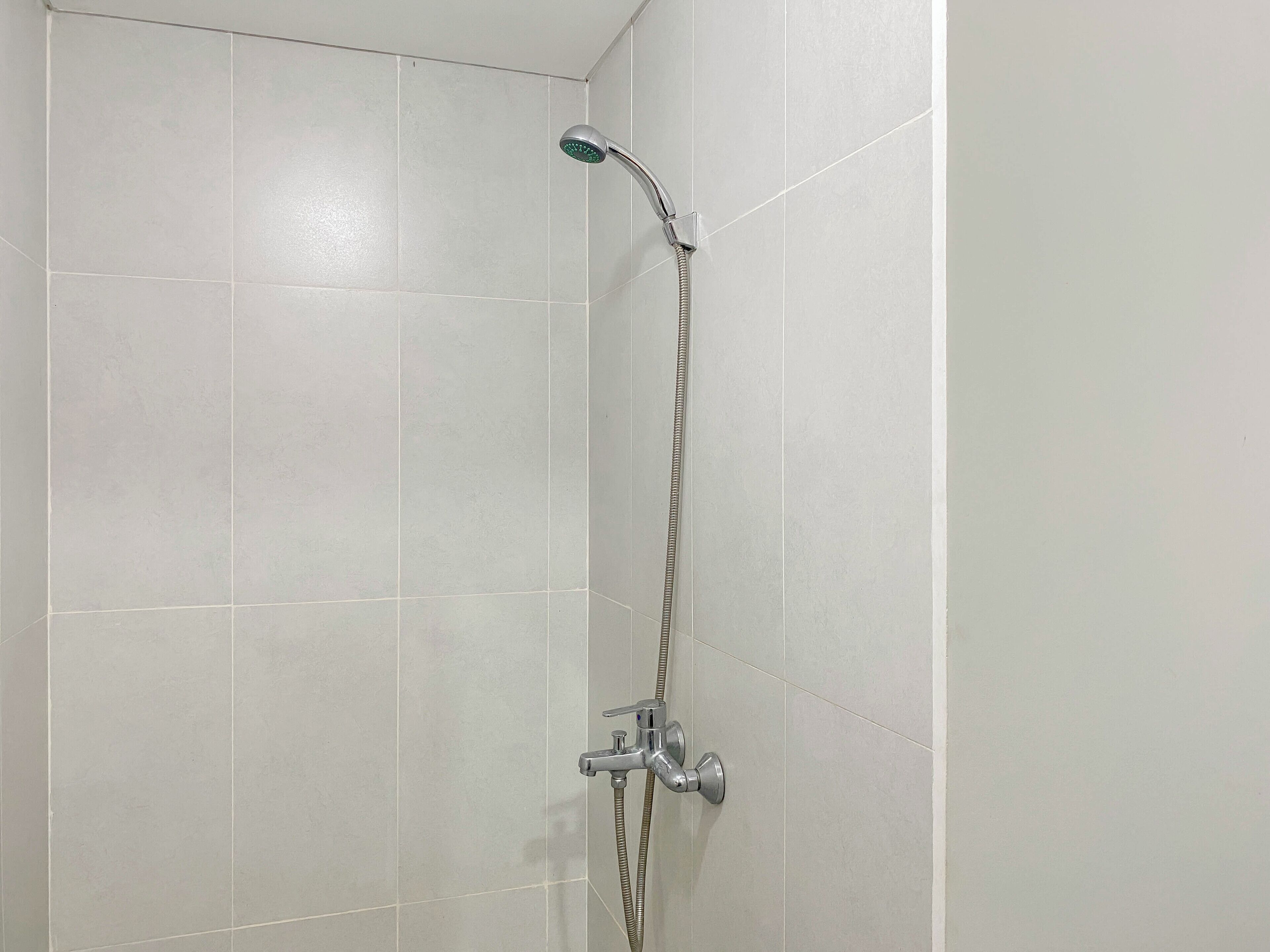 Um chuveiro com um chuveirinho manual e uma mangueira manual.