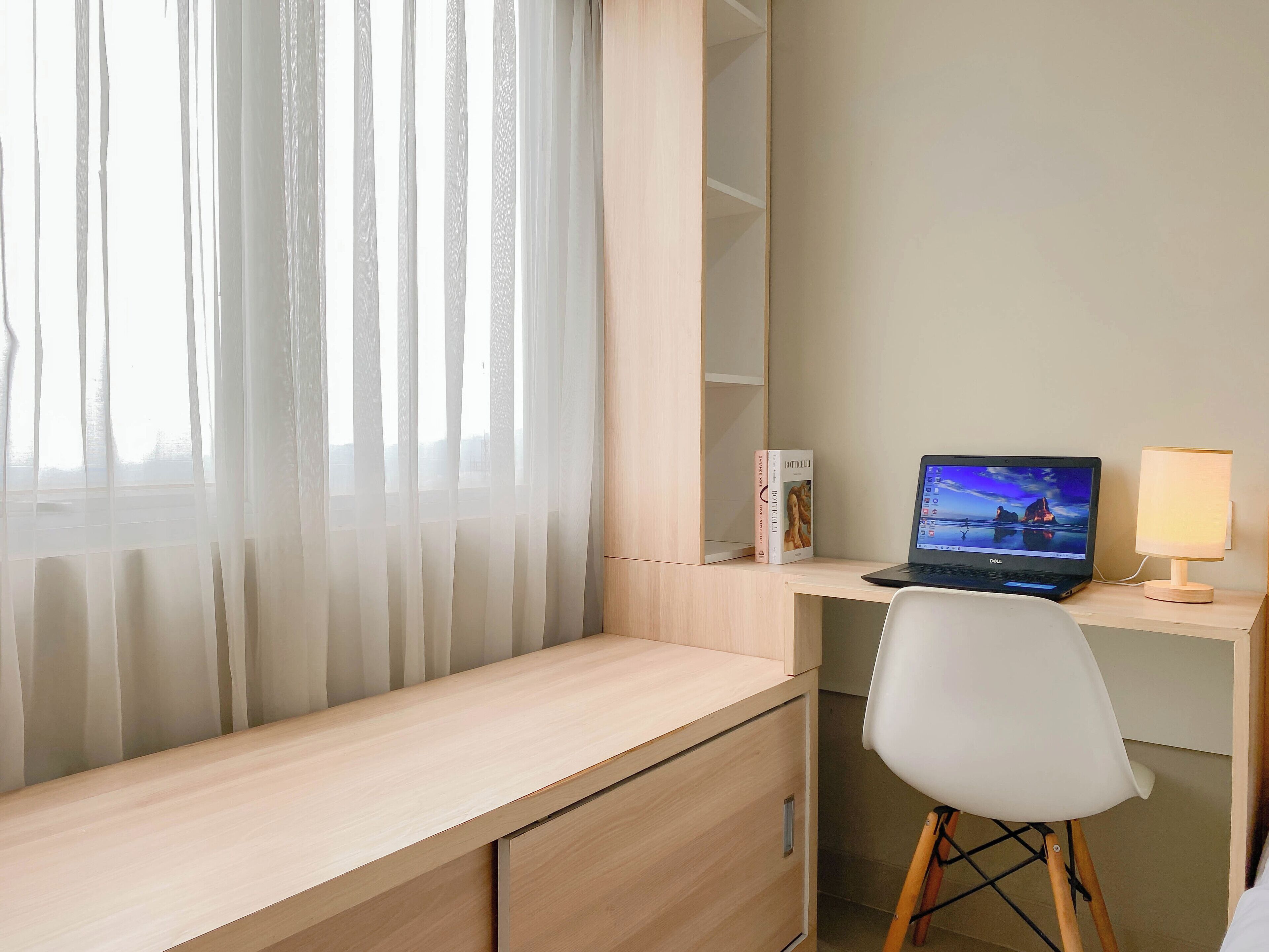 A modern office space with a desk, chair, laptop, and a lamp.