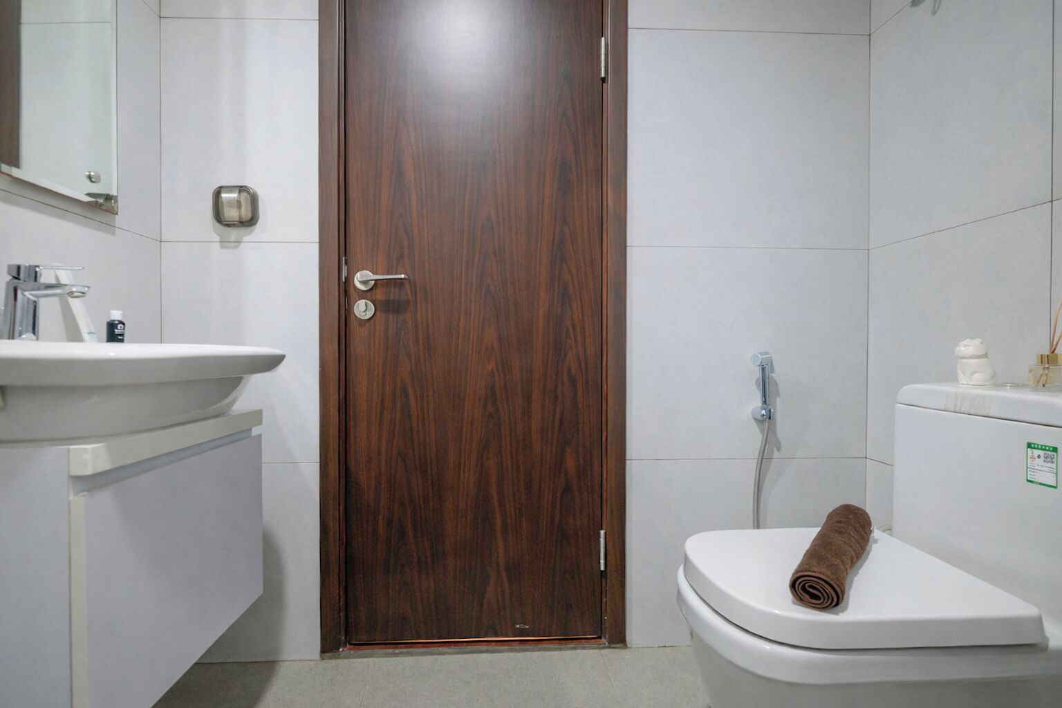 A bathroom with a wooden door, a white sink, and a toilet.