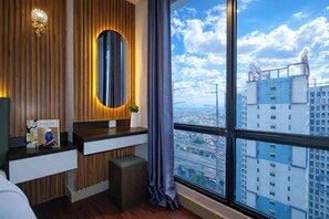 A modern hotel room with a wooden wall, a large window with a city view, a vanity with a mirror, and a small bench. - Urban Living Studio At Lrt City Bekasi Apartment (Bekasi)