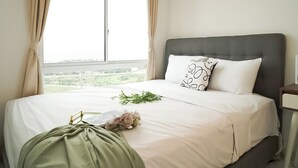 Een hotelkamer met een bed, nachtkastje en een raam met gordijnen.